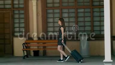 带手提箱的女孩在假日旅行时抵达老电影火车站